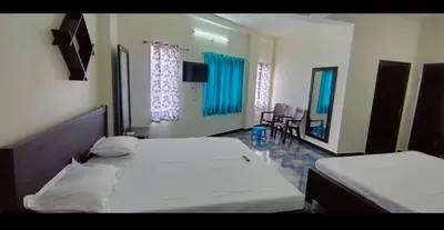 two beds in a bedroom with blue curtains at Arulmozhi Dream in Ooty