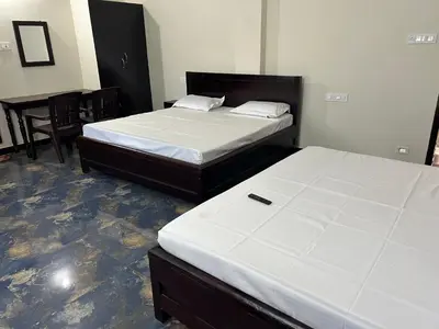 a bedroom with two beds and a table and chairs at Arulmozhi Dream in Ooty