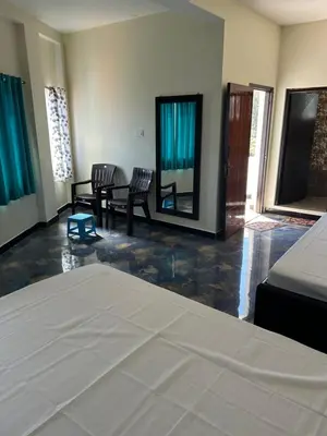 a room with a bed and a table and chairs at Arulmozhi Dream in Ooty