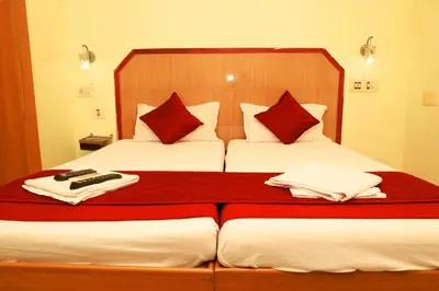 a bedroom with two beds with red and white pillows at KG Grand Inn in Erode
