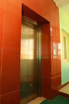 a metal elevator in a room with red walls at KG Grand Inn in Erode