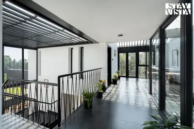 a hallway of a house with glass doors and plants at StayVista at Lotus Lumiere with Breakfast & jacuzzi in Madikeri