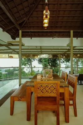 a wooden table and chairs in a room at Nila Paithal in Paithalmala