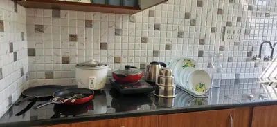a kitchen counter with a stove with pots and pans at 2BHK Flat by SR Renton Comfort Homestay Mysore @ Vijayanagar 2nd stage Mysore in Mysore