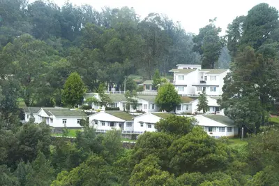 a group of white houses in the trees at Sabol Holidays in Ooty