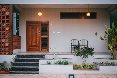 a house with a wooden door and some plants at Poojaris Nirantara - Mysuru in Hampāpura