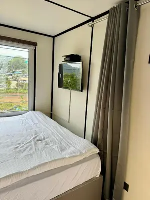 a bedroom with a bed and a window at The Jade Highlands Mountain View Container Studio Room in Kodaikānāl