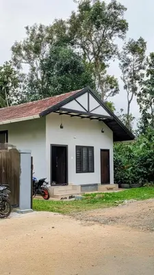 a small white house with a black roof at Meghamalhar in Mānantoddy