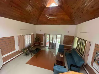 a living room with a ceiling fan and blue chairs at 'Vrindavan' in Heritage City Mysuru in Mysore