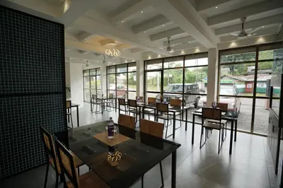 a dining room with tables and chairs and windows at Sreeja Myst in Athirappilly