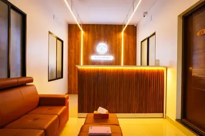 a lobby with a leather couch and a wall at Adam homes in Alwaye