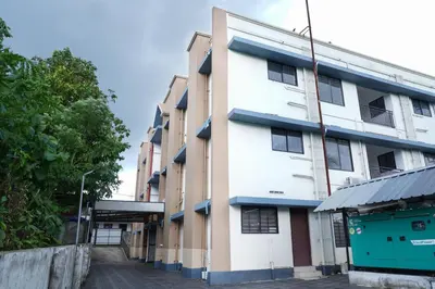 a white building with blue trim next to a street at Adam homes in Alwaye