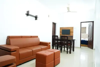 a living room with a couch and a dining room at Adam homes in Alwaye