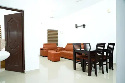 a living room with a couch and a table and chairs at Adam homes in Alwaye