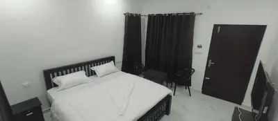 a bedroom with a bed with white sheets and a door at Kashmir Valley in Kanthalloor