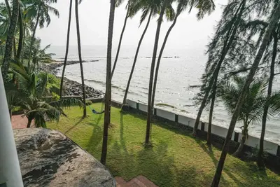 a view of a beach with palm trees and the ocean at Baywatch by Grha - A Picturesque Beachfront Villa in Kozhikode