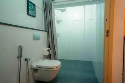 a bathroom with a toilet and a glass shower at Baywatch by Grha - A Picturesque Beachfront Villa in Kozhikode