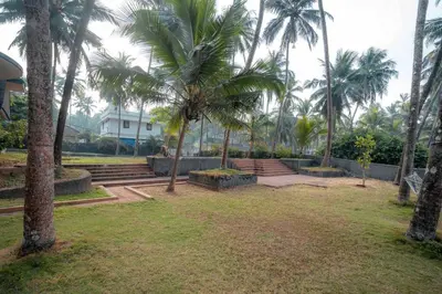 a park with palm trees and steps and a building at Baywatch by Grha - A Picturesque Beachfront Villa in Kozhikode