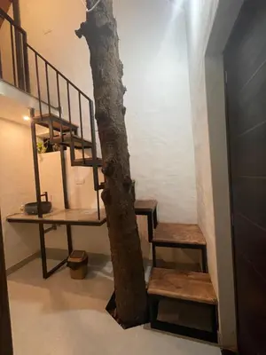 a tree in the middle of a room with stairs at Senthamarai villa in Sultan Bathery