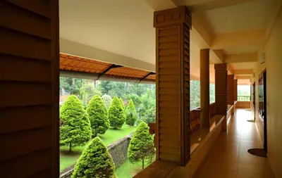 a hallway with a view of a garden through a window at Peter's Coffee Creek Wayanad Pool Resort in Wayanad