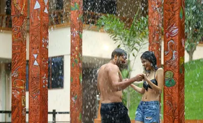 a man and a woman standing in the rain at Peter's Coffee Creek Wayanad Pool Resort in Wayanad