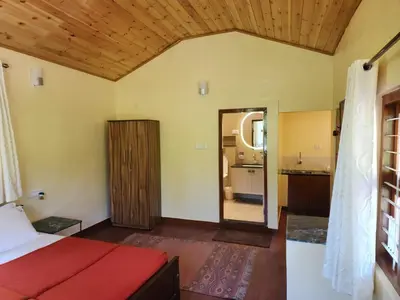 a bedroom with a red bed and a bathroom at Aranyasun in Masinagudi