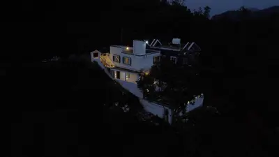 a large white house on a hill at night at Casa de Selas in Coonoor