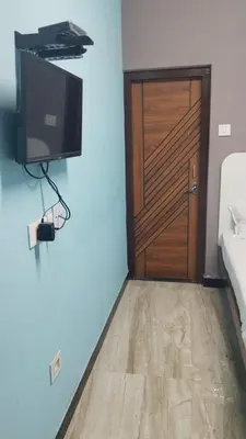 a room with a wooden door and a television and a floor at Misty Stay by Le Apex in Ooty
