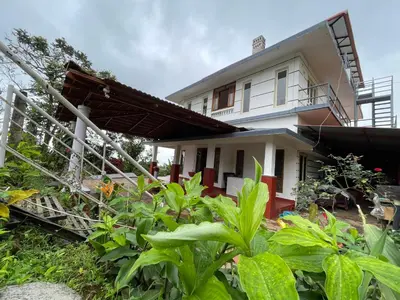 a white house with a fence and some plants at ABODE Backpacker's Hostel in Madikeri