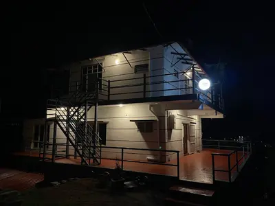 a building with a clock on the side of it at night at ABODE Backpacker's Hostel in Madikeri