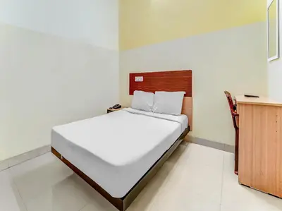 a bedroom with a white bed and a wooden cabinet at Sri Balaji castle in Coimbatore