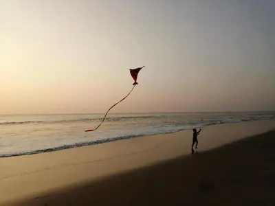 a person is flying a kite on the beach at Ocean Whisper- psst! hidden gem in Kaipamangalam