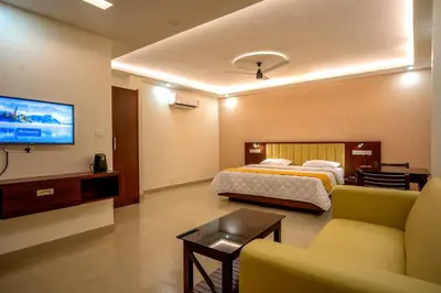 a bedroom with a bed and a couch and a tv at Metro Residency in Tirūr