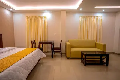 a hotel room with a bed and a couch and tables at Metro Residency in Tirūr