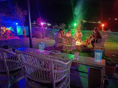 a group of people sitting around a fire at night at Mountain View Private Villa in Ooty