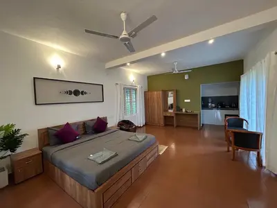 a bedroom with a large bed with a ceiling fan at Mahogany by Exuberance Stays in Wayanad
