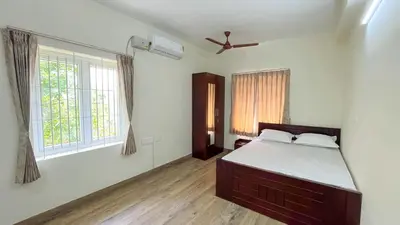 a bedroom with a bed and two windows at Thapovan coimbatore in Coimbatore