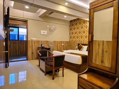 a bedroom with a bed and a desk and a chair at Alicos Residency in Sultan Bathery