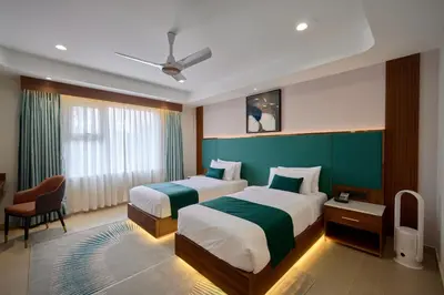 a hotel room with two beds and a window at Kowju Airport Hotel Calicut in Kondotti