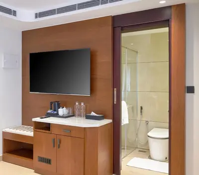 a bathroom with a television on a wall with a toilet at Kowju Airport Hotel Calicut in Kondotti
