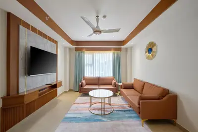a living room with a couch and a tv at Kowju Airport Hotel Calicut in Kondotti