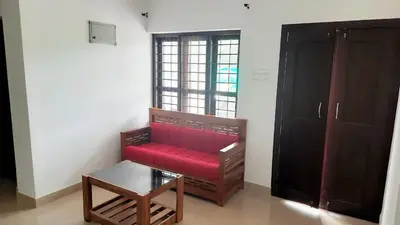 a red couch in a room with a window at Brighton Retreat in Sultan Bathery