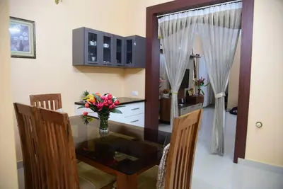 a dining room table with a vase of flowers on it at S R Luxurious Fully Ac 3 BHK Bunglow Mysore in Mysore