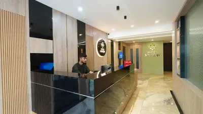 a man sitting at a counter with a laptop at Hotel Hive Inn - Kozhikode in Kozhikode