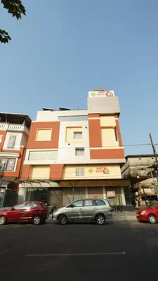 a building with cars parked in front of a street at Hotel Hive Inn - Kozhikode in Kozhikode