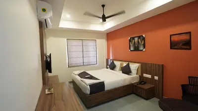 a bedroom with a bed with an orange wall at Hotel Hive Inn - Kozhikode in Kozhikode