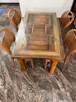 a wooden table with two chairs and a glass top at Montage Villa in Kozhikode