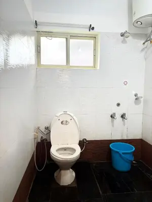 a bathroom with a toilet and a blue bucket at Earth songs by Green leaves - 10 kms from kotagiri in Kotagiri