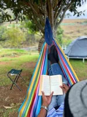 a person laying in a hammock reading a book at Earth songs by Green leaves - 10 kms from kotagiri in Kotagiri