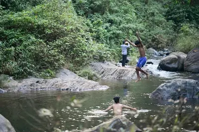 two men playing in the water in a river at BLUE CREEK in Meppādi